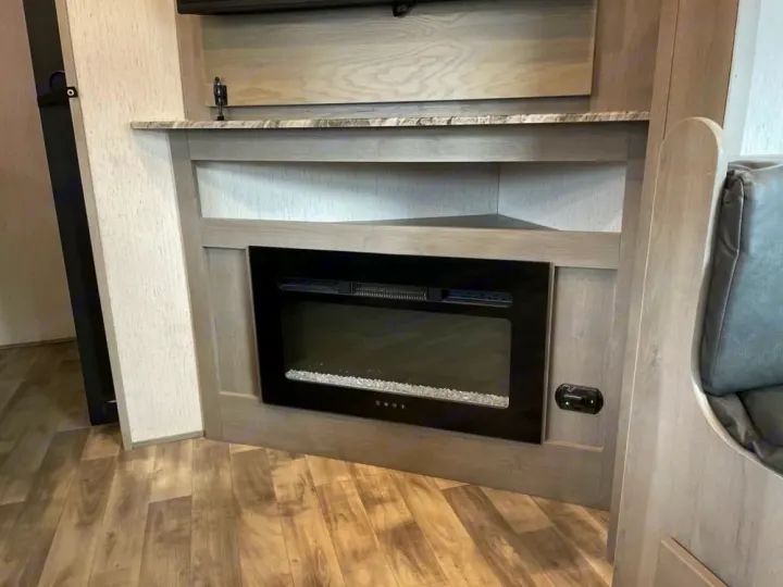 Inside your modern RV rental: a built-in electric fireplace provides warmth and ambiance in this light-toned living area.. Dutchmen Kodiak Ultra Lite 2022
