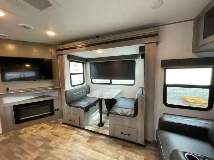 Spacious RV rental interior featuring a cozy dinette, modern entertainment center with TV & fireplace.. Dutchmen Kodiak Ultra Lite 2022