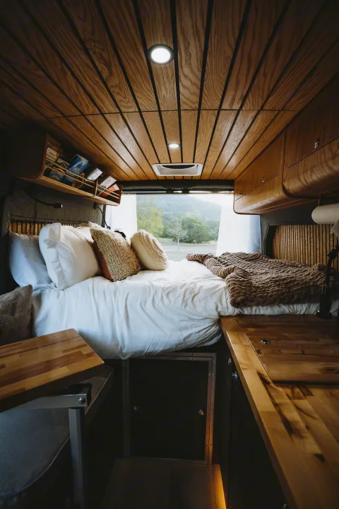 Cozy RV rental interior with a comfy bed, wood ceiling, and stunning nature views. Perfect for adventure!. Dodge 1500 2020