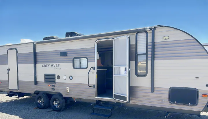 RV rental: A Grey Wolf travel trailer with its door open, showing steps, dual axles, and an awning under a clear sky.. Forest River Cherokee 2017