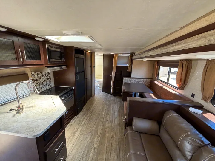 Comfortable RV rental interior: modern kitchen, dinette, sofa living area, and bathroom visible down the hall.. Forest River Cherokee 2017