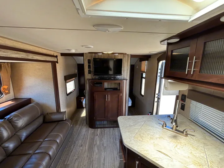 Experience comfort in this spacious RV rental interior, featuring a cozy living area, modern kitchen, and entertainment center for travel.. Forest River Cherokee 2017