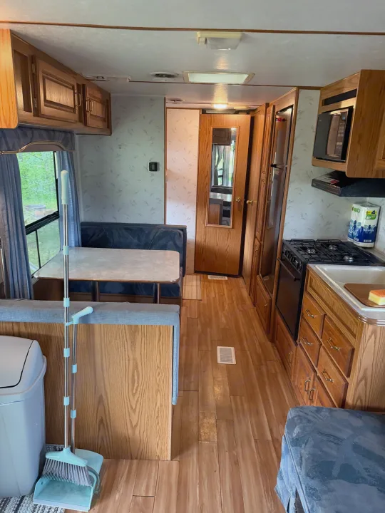 RV rental featuring a compact kitchen with stove/microwave, a dinette, and bright wood-look flooring.. Jayco 300dbbh 1994