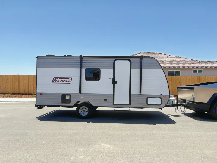 Grey & white Coleman travel trailer, perfect for rv rental, hitched to a modern truck. Ready for sunny road trips!. Dutchmen Coleman 2024