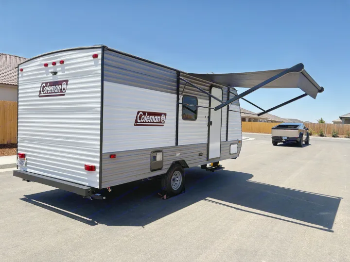 Coleman RV rental with extended awning, a Cybertruck is in the background on a sunny day.. Dutchmen Coleman 2024