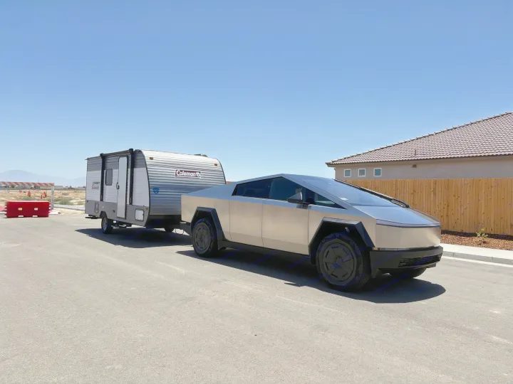 Silver Tesla Cybertruck towing a Coleman RV rental, parked on asphalt under a clear blue sky.. Dutchmen Coleman 2024