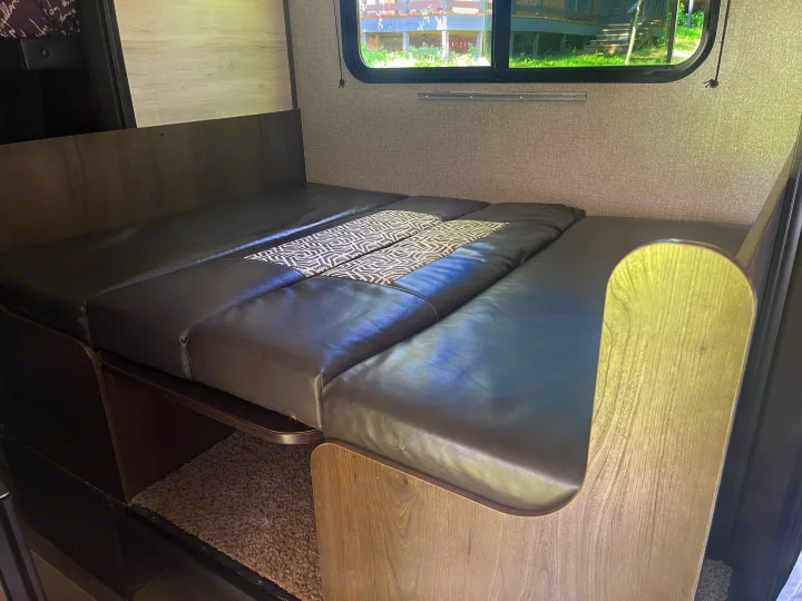Inside an RV rental: This functional dinette converts to a comfortable bed with dark grey cushions.. Jayco Jay Flight SLX 2021