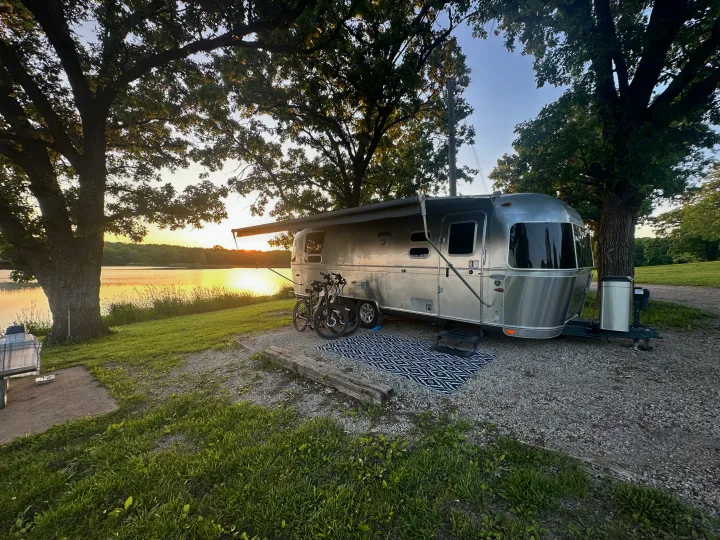 Lakeside Airstream RV rental at sunset, parked with bikes at a serene campsite.. Airstream Flying Cloud 2012