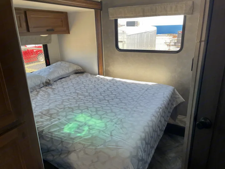RV rental: Modern bedroom interior with patterned bedding, overhead cabinets, and bright natural light.. Forest River Sunseeker 2022