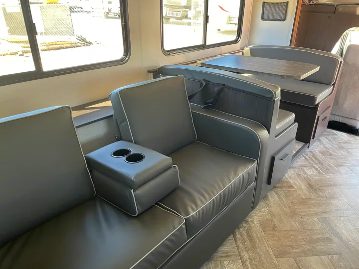 RV rental interior: comfy dark grey sofa with cupholders, dinette, and stylish wood-look floor. Ready for travel!. Forest River Sunseeker 2022