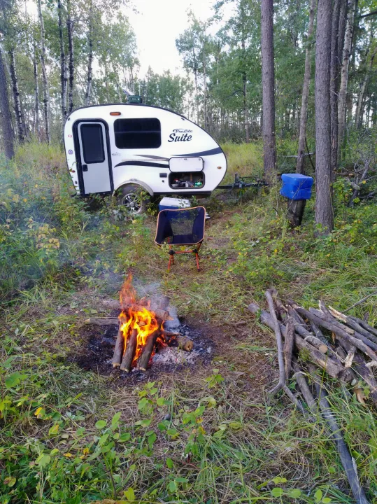 Relaxing rv rental setup: ProLite Suite camper, crackling campfire, and chair in a peaceful forest clearing.. Prolite Prolite Trailer 2018