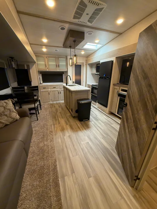 Spacious, modern RV rental interior with full kitchen and living area, featuring light wood finishes and ample light.. Forest River Impression 2022