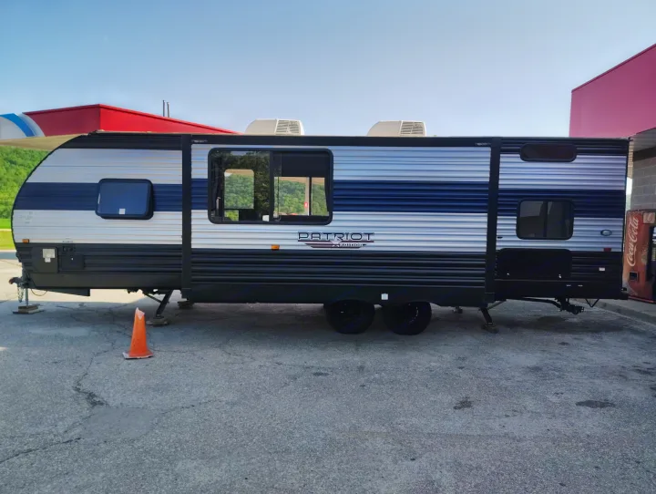 RV rental: A blue and silver "Patriot Edition" travel trailer parked on asphalt, ready for your next adventure.. Forest River Patriot 274BRB 2022