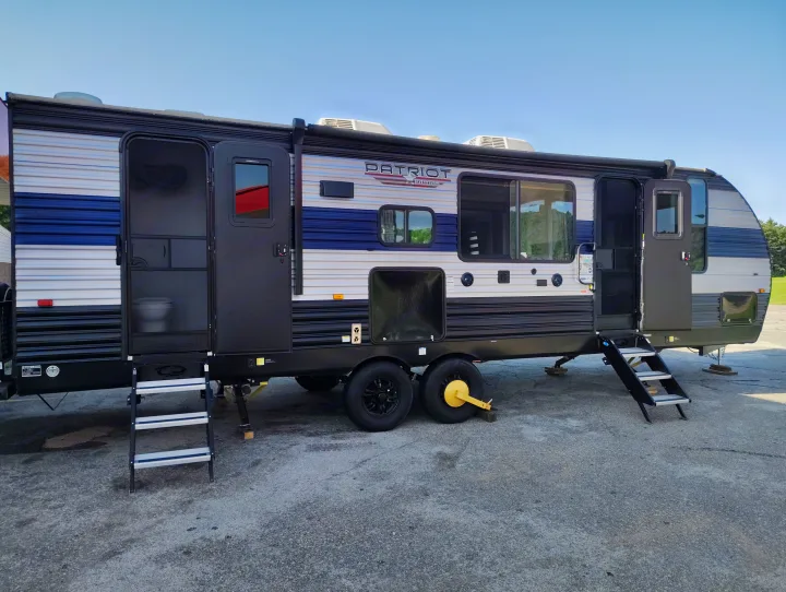 This RV rental is a sleek travel trailer with open doors and steps, ready for adventure. A perfect home on wheels.. Forest River Patriot 274BRB 2022