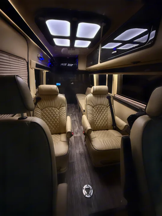 Luxurious RV rental interior: cream quilted seats, wood-look floor, and ample lighting for comfortable travel.. Ultimate Toys Ultimate RV 2021
