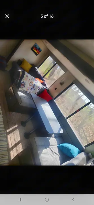 RV rental: Cozy dinette area with grey seating, table, windows showing trees, and colorful pillows and blanket.. Forest River Cherokee 2020