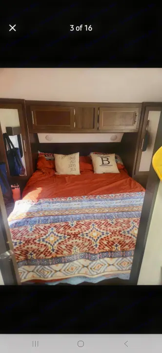 RV rental bedroom showcasing a cozy bed with orange sheets, a patterned blanket, and built-in storage cabinets.. Forest River Cherokee 2020