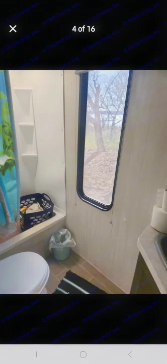 RV rental bathroom with a compact shower, toilet, sink, and a window offering a serene nature view.. Forest River Cherokee 2020
