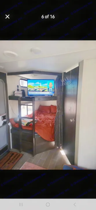 Cozy RV rental interior featuring bunk beds with red bedding, a TV, and a functional small space.. Forest River Cherokee 2020