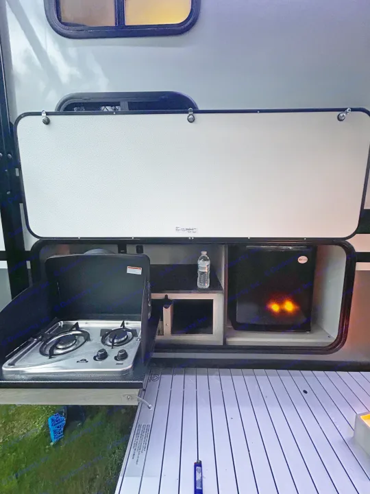 This RV rental's open outdoor kitchen features a two-burner stove, mini-fridge, and extending table.. Coachmen Apex Nano 2023