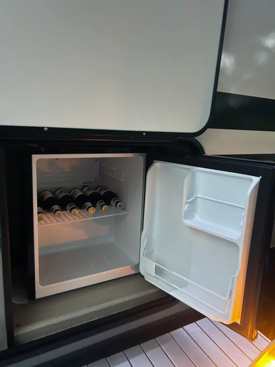 RV rental: An open mini-fridge reveals bottles inside, ready for cool drinks on your next road trip.. Coachmen Apex Nano 2023