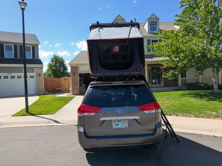 Toyota Sienna minivan with a deployed rooftop tent, ready for an RV rental outdoor adventure.. Toyota Sienna 2012