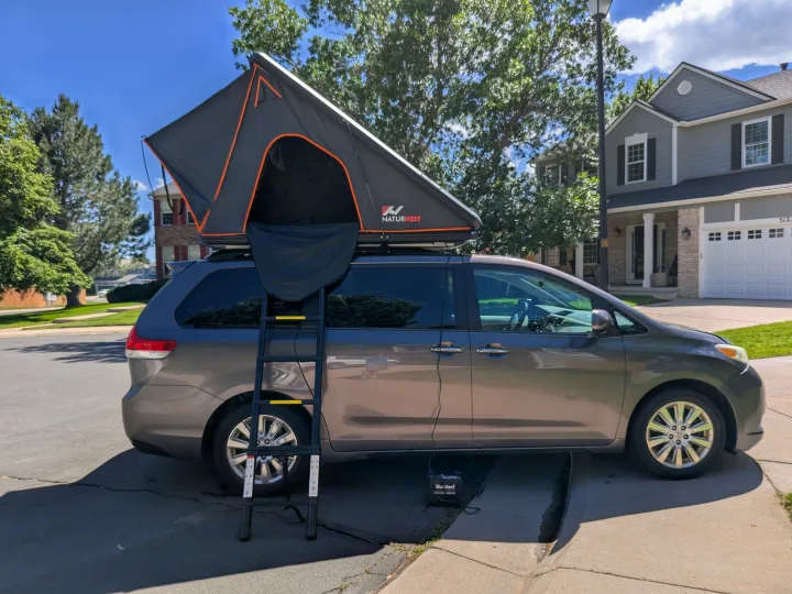 Compact RV rental: A minivan with a deployed NaturNest rooftop tent and ladder, ready for adventures.. Toyota Sienna 2012