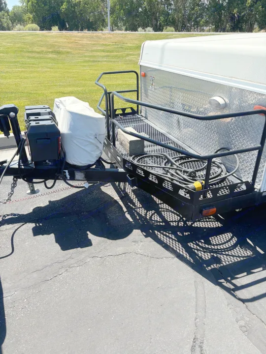 Close-up of a utility trailer's hitch and front cargo area, featuring batteries and a platform with power cords for an RV rental.. Rockwood Freedom 2280 BH 2016