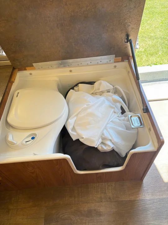 RV rental interior: Thetford portable toilet and stored shower accessories inside a compact compartment. Efficient RV bathroom setup.. Rockwood Freedom 2280 BH 2016