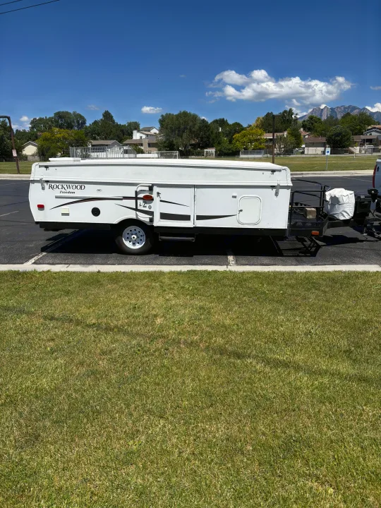 White Rockwood Freedom pop-up camper for rv rental, parked on a sunny day. Ideal for outdoor adventures.. Rockwood Freedom 2280 BH 2016