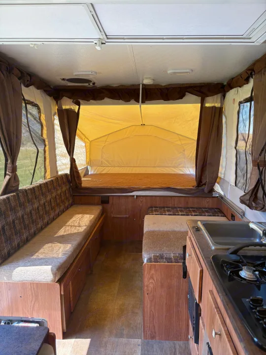 Cozy pop-up RV rental interior with beds, seating, and kitchenette visible from the entrance.. Rockwood Freedom 2280 BH 2016