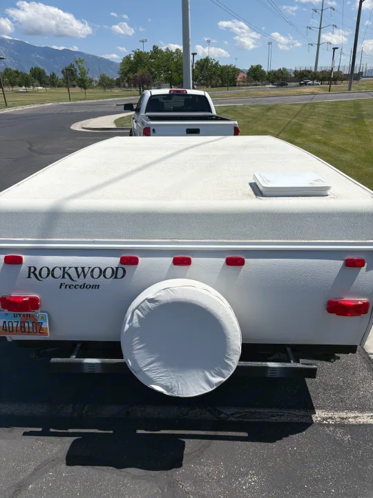 Rear view of a white Rockwood Freedom pop-up camper, an RV rental, with mountains in the distance.. Rockwood Freedom 2280 BH 2016