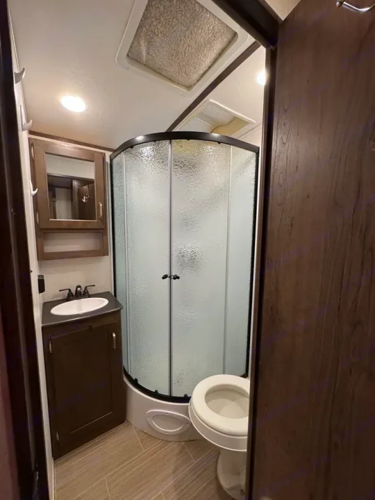 Functional RV rental bathroom with a compact corner shower, toilet, and sink. Ready for your next adventure!. Keystone RV 3400QD 2020