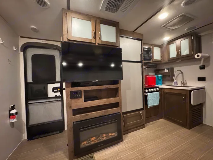RV rental: Bright, modern interior featuring kitchen with appliances, sink, TV, and cozy fireplace.. Keystone RV 3400QD 2020