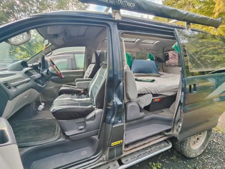 Open RV rental campervan shows driver's area, custom bed, & a roof awning. Ready for your next diesel-powered adventure.. MITSUBISHI Delica 1997
