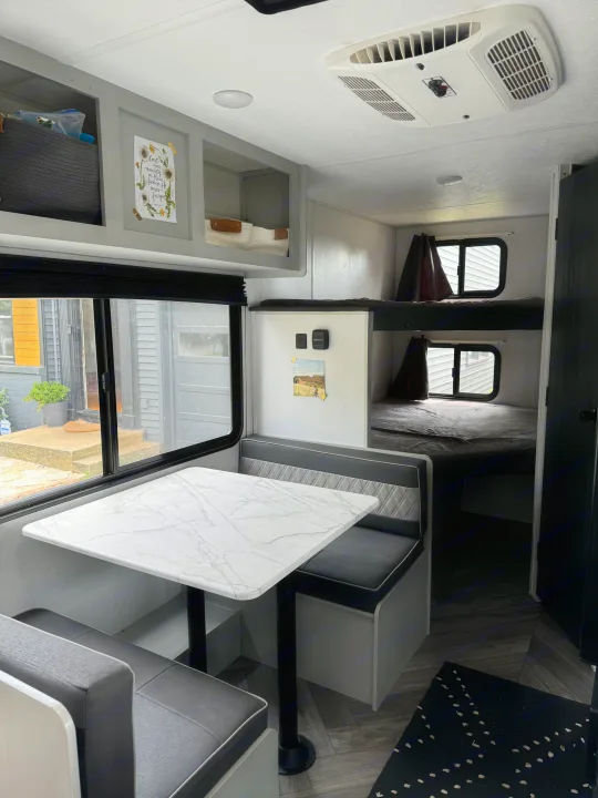 This RV rental showcases a bright dinette area, ample overhead storage, AC unit, and comfortable bunk beds for travel.. Forest River Salem FSX 2022