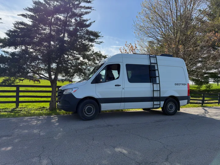 Experience nature with this Geotrek rv rental! White adventure van parked by a serene horse farm & green fields.. Mercedes-Benz Sprinter 2024