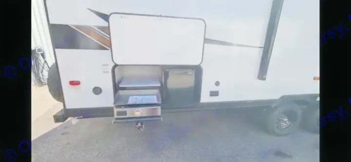 Side view of an RV rental, showcasing an outdoor kitchen with a griddle, shelf, and mini-fridge. Perfect for camping.. Forest River Wildwood X-Lite 2023