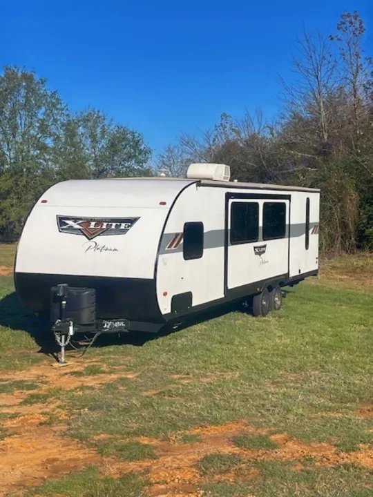 Bright white travel trailer RV on a grassy lot, ideal for your next outdoor rv rental adventure.. Forest River Wildwood X-Lite 2023