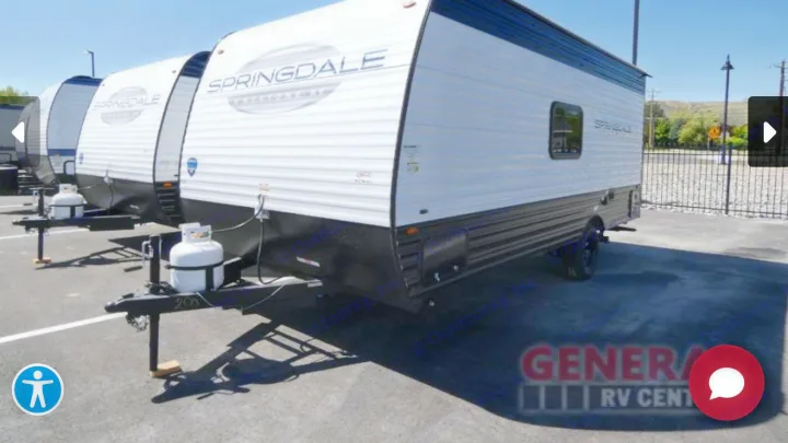 Row of white Springdale travel trailers, perfect for your next RV rental adventure, parked on asphalt.. Keystone Springdale 2025