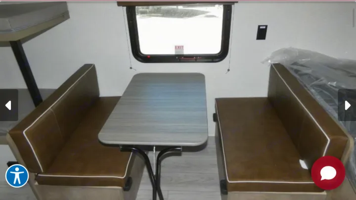 RV rental interior: dinette with brown benches, a grey table, and a window above. Bunk bed frame visible on left.. Keystone Springdale 2025