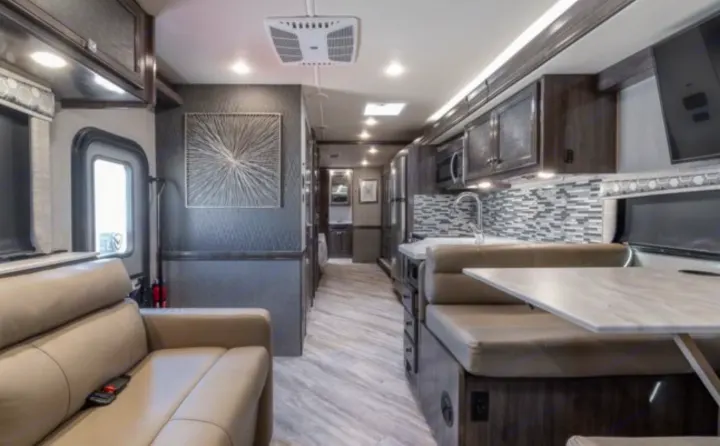 Spacious RV rental interior featuring a modern kitchen, dining booth, and comfortable living area.. Holiday Rambler Invicta 2021