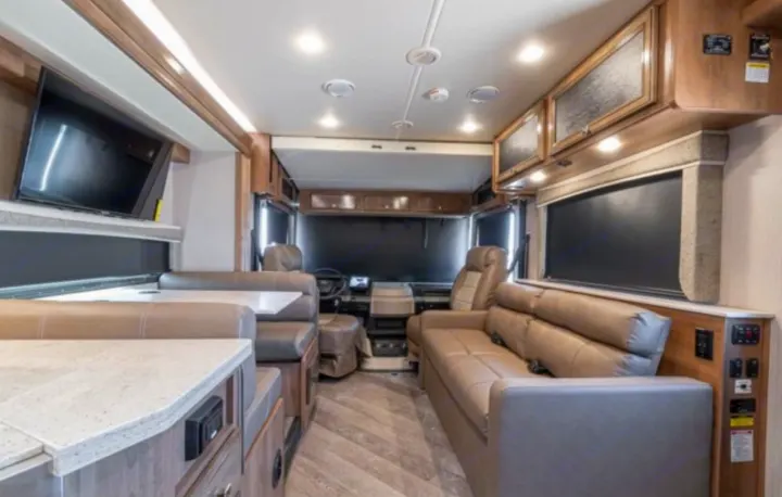 Spacious RV rental interior showcasing a cozy dinette, comfortable sofa, and front cockpit.. Holiday Rambler Invicta 2021