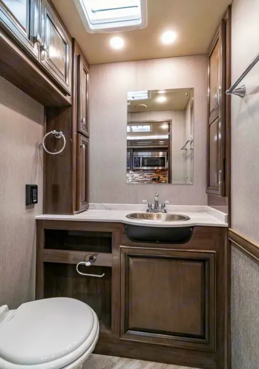 Well-appointed RV rental bathroom featuring a sink vanity, toilet, and ample storage for comfortable travel.. Holiday Rambler Invicta 2021