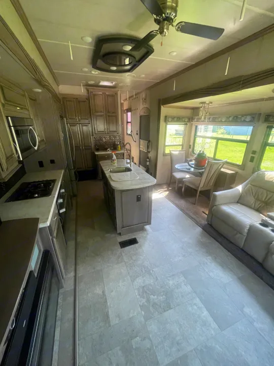 Spacious, modern RV rental interior featuring a full kitchen with island, dining area, and comfortable recliners in the living space.. Cedar Creek Champagne 2019