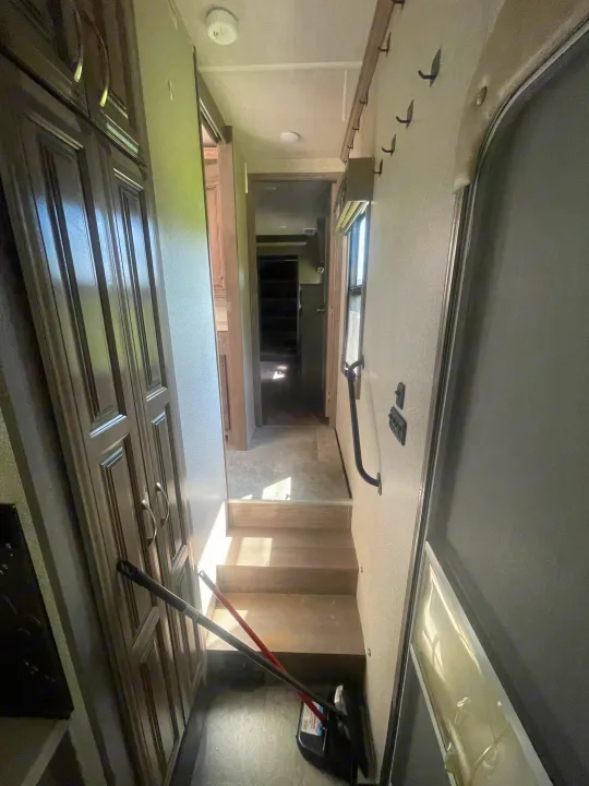 RV rental: Bright interior view of an RV hallway with steps, wooden storage, and the main entry door leading to living spaces.. Cedar Creek Champagne 2019