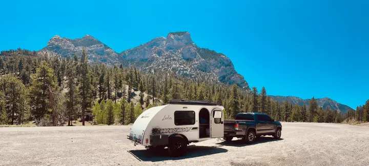 A Tacoma truck tows a compact teardrop RV rental, parked in a scenic mountain and forest landscape. Ready for adventure!. InTech RV InTech RV Trailer 2021