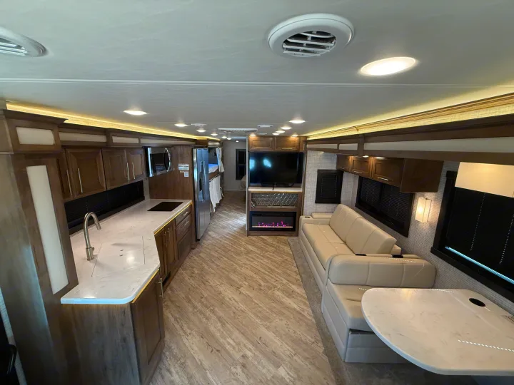 Spacious, modern RV rental interior features a full kitchen, comfortable living area with TV & fireplace, and bright lighting.. Jayco Seneca 2025