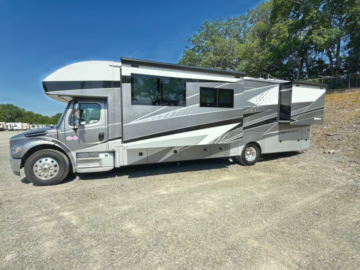 Experience freedom with this large grey and white Super C motorhome RV rental, parked on gravel with slide-outs extended.. Jayco Seneca 2025