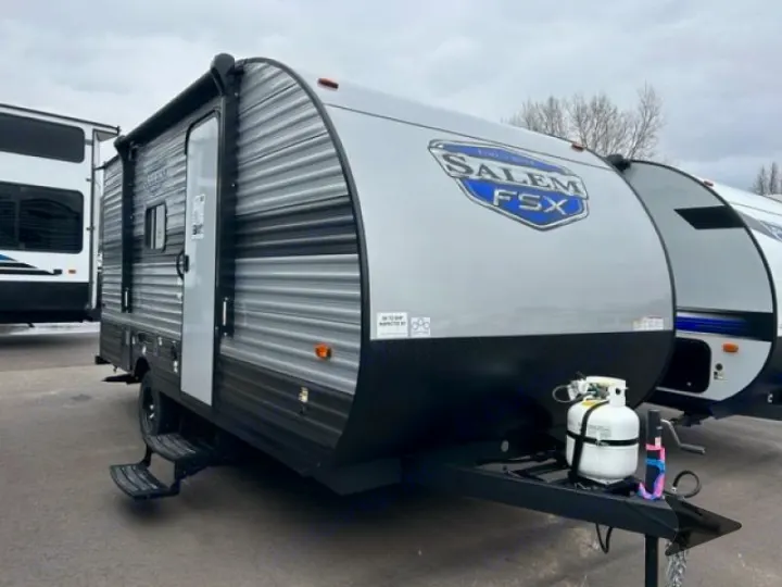 Compact grey Salem FSX travel trailer, ideal for rv rental. Note the awning, entry door, and front propane tanks.. Forest River Salem 2024